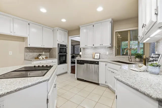 a kitchen with granite countertop cabinets a sink a counter and stainless steel appliances