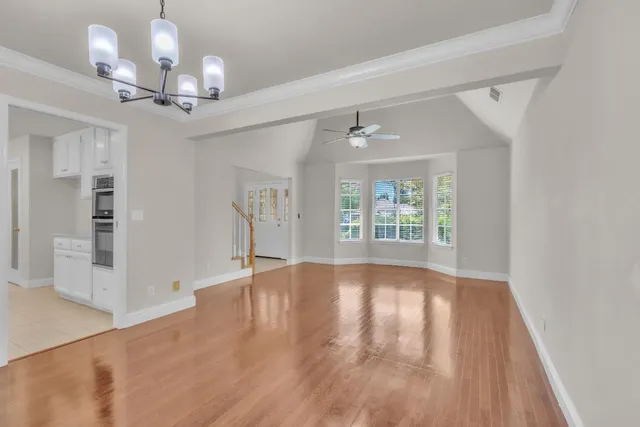 a view of an empty room with wooden floor fireplace and a window