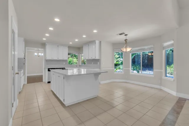 a kitchen with stainless steel appliances kitchen island granite countertop a refrigerator a sink and a stove