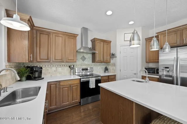 a kitchen with a stove a refrigerator a sink a dining table and chairs with wooden floor