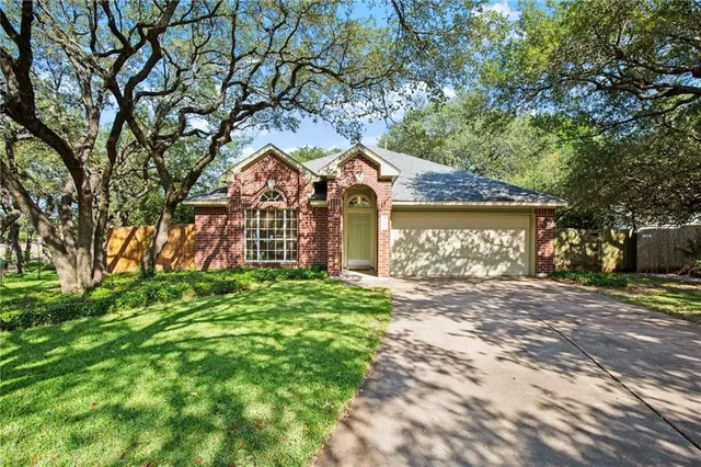 a front view of a house with a garden and trees