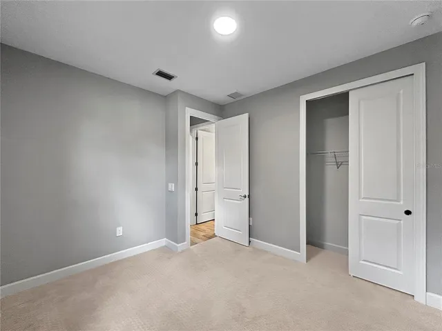 a large white kitchen with a large counter space a sink stainless steel appliances and cabinets