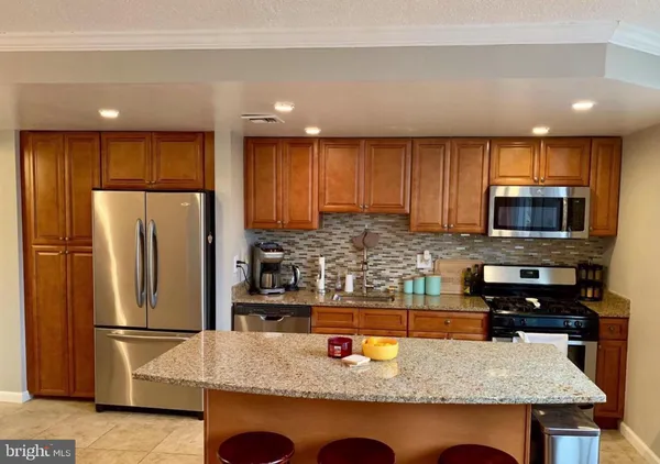 a kitchen with stainless steel appliances granite countertop a refrigerator a stove a sink a microwave and a refrigerator