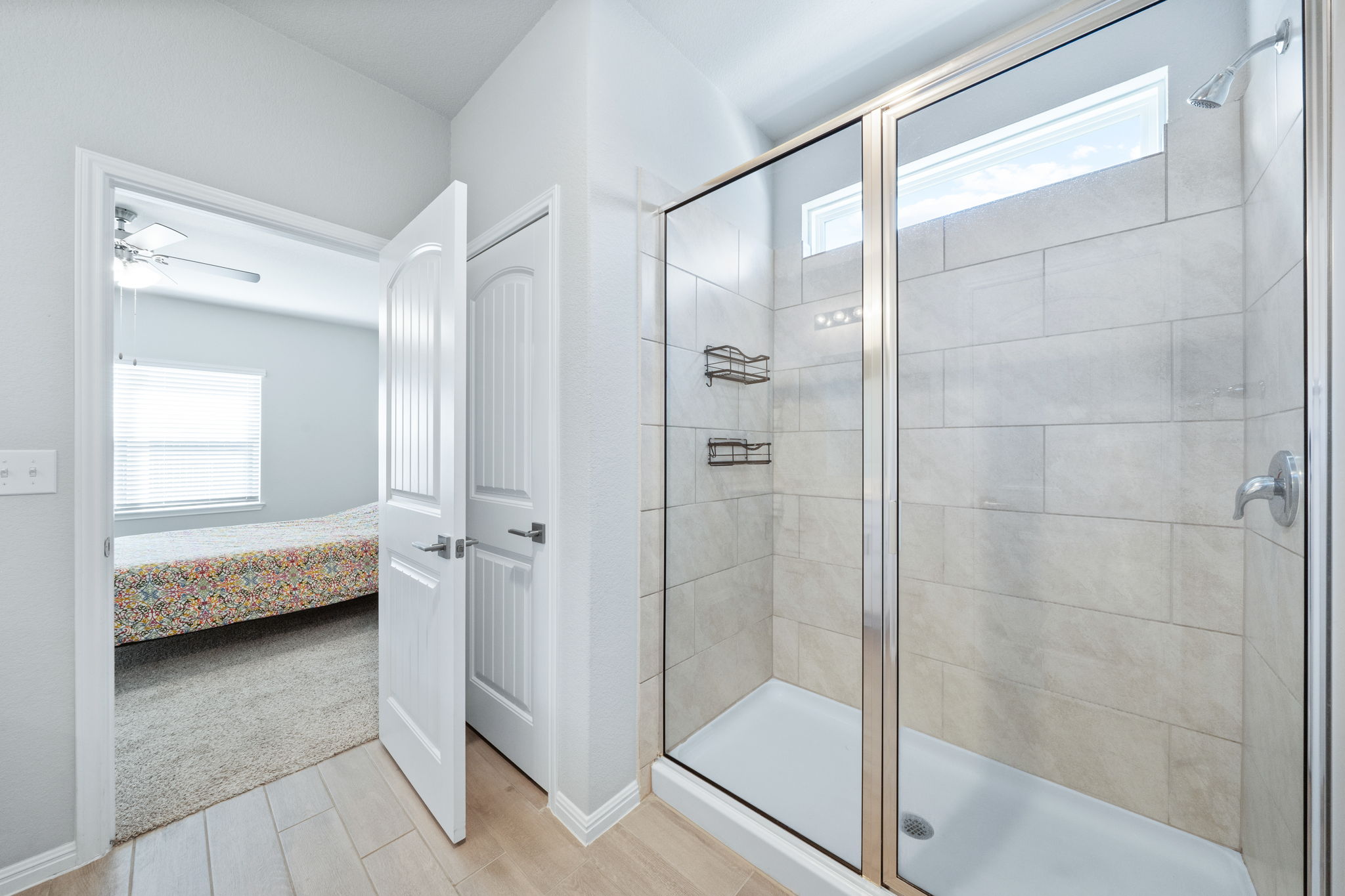 2412 Starhill Ranch Street Georgetown, TX 78628 - Photo 29 of 40 A well-appointed shower with glass enclosure and tiled walls complements a bright adjoining room with wood flooring.