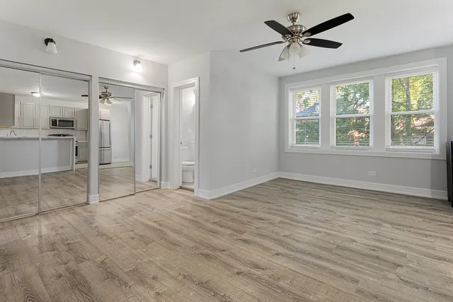 a view of empty room with wooden floor and fan