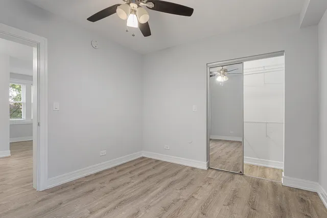 an empty room with wooden floor cabinet and windows