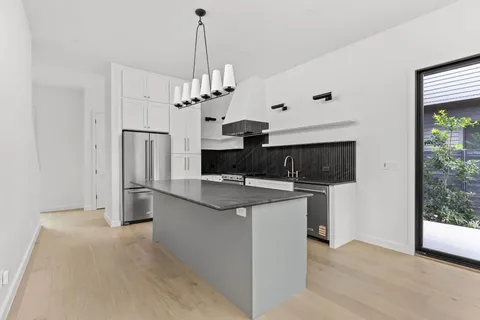a view of a kitchen with stainless steel appliances granite countertop a refrigerator and a stove top oven
