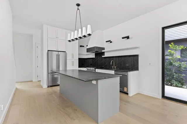 a view of a kitchen with stainless steel appliances granite countertop a refrigerator and a stove top oven