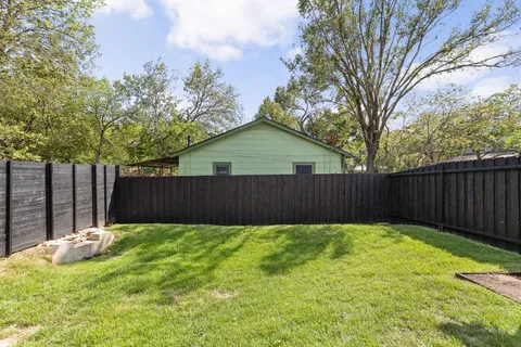 a view of a backyard with wooden fence and a large tree