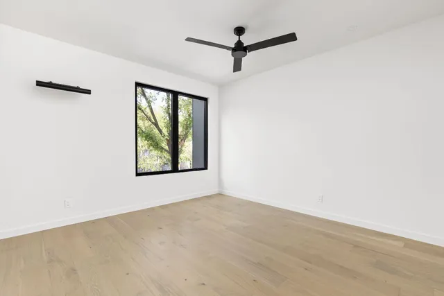 an empty room with windows and fan