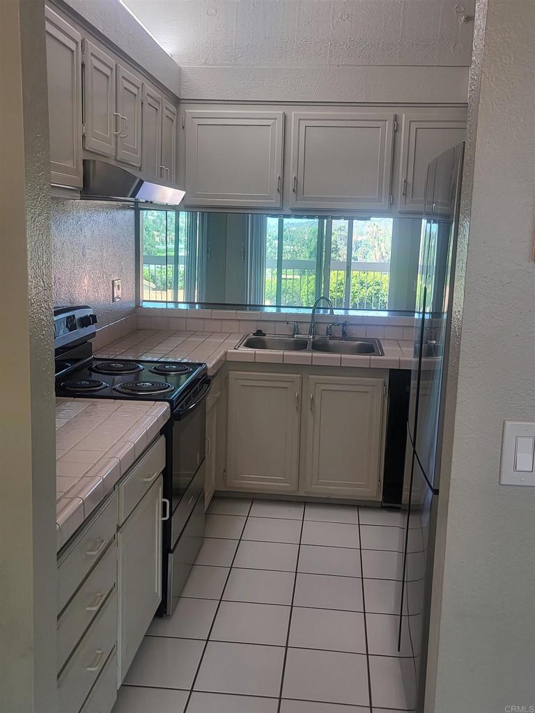 2319 Caringa Way, Unit 56 Carlsbad, CA 92009 - Photo 11 of 24 a kitchen with a sink a stove cabinets and a window