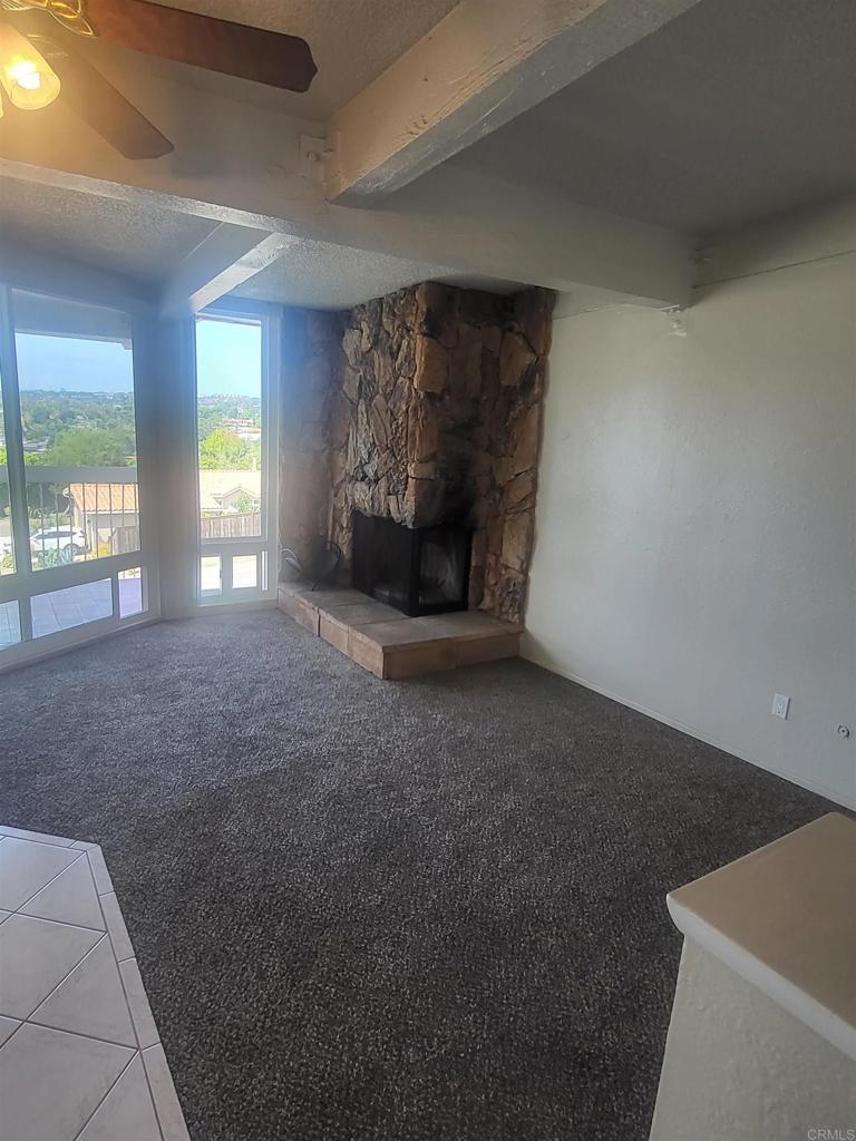 2319 Caringa Way, Unit 56 Carlsbad, CA 92009 - Photo 10 of 24 a view of an empty room with a fireplace and a window