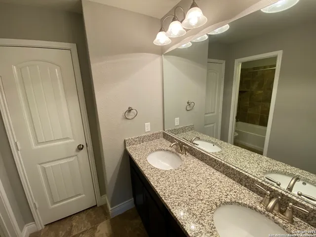 a bathroom with a granite countertop sink a mirror and a shower