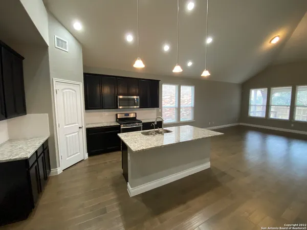 a large kitchen with a large counter top stainless steel appliances and cabinets