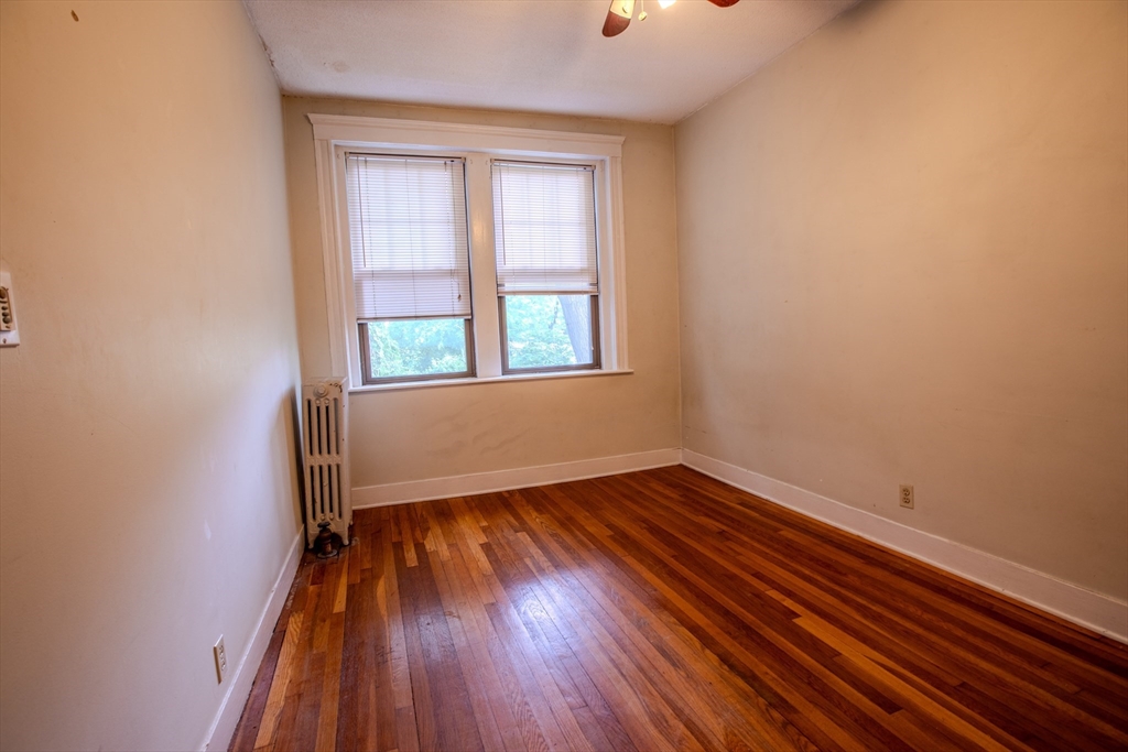 153 Strathmore Road, Unit 4 Boston, MA 02135 - Photo 3 of 9 an empty room with wooden floor and windows