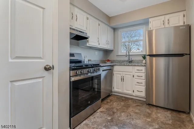 a kitchen with stainless steel appliances white cabinets and a refrigerator
