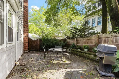 a view of a patio with table and chairs potted plants and large tree