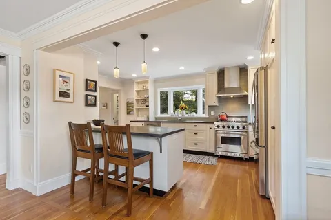a kitchen with stainless steel appliances a dining table chairs stove refrigerator and cabinets