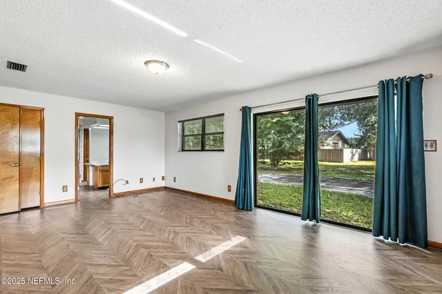 a view of an empty room with glass door and a window
