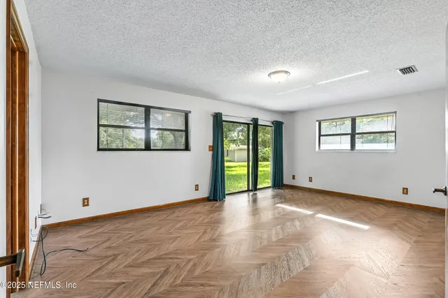 a view of an empty room with window and a kitchen