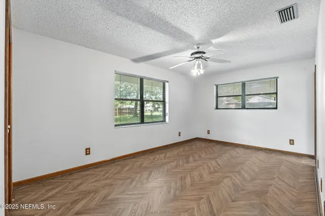 an empty room with windows and ceiling fan
