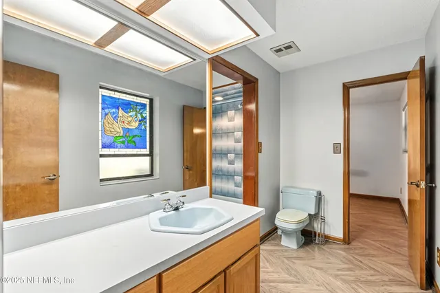 a spacious bathroom with a granite countertop sink a toilet a mirror and shower