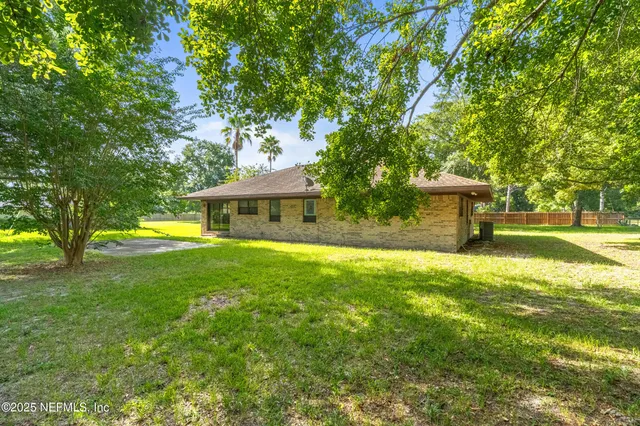 a front view of a house with a yard and a tree