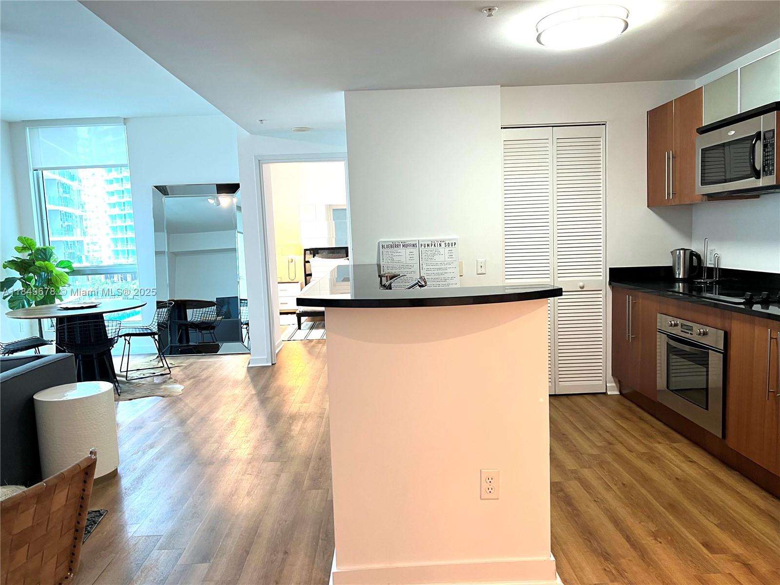 300 South Biscayne Boulevard, Unit T1602 Miami, FL 33131 - Photo 10 of 20 a kitchen with granite countertop a stove a sink a refrigerator and wooden floor