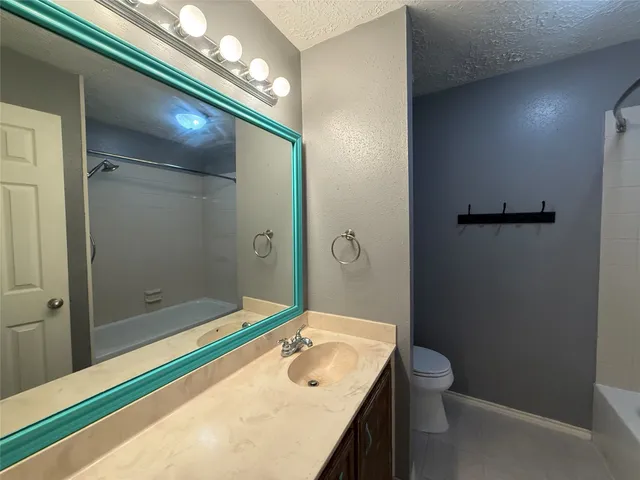 a bathroom with a granite countertop sink a toilet and shower