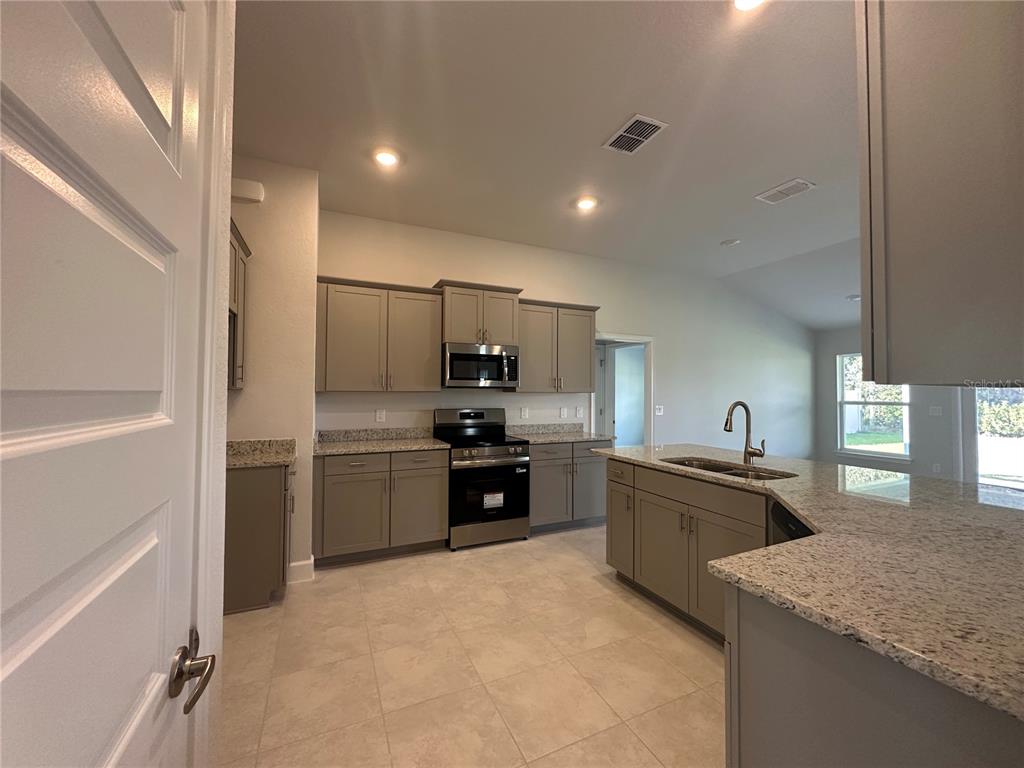 4413 Southwest 90th Place Ocala, FL 34476 - Photo 4 of 17 a large kitchen with a stove a sink dishwasher a refrigerator and a stove with wooden floor