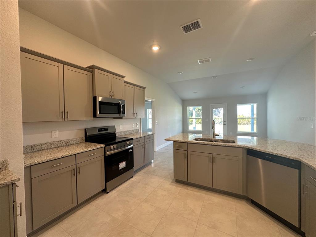 4413 Southwest 90th Place Ocala, FL 34476 - Photo 6 of 17 a kitchen with stainless steel appliances granite countertop a sink and stove top oven