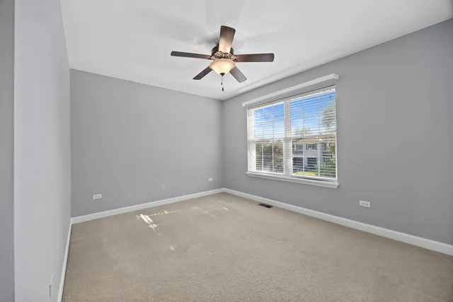 an empty room with windows and ceiling fan