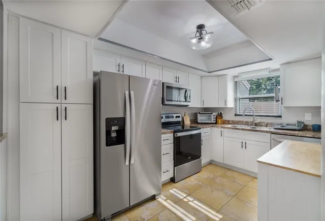 a kitchen with a refrigerator a sink stainless steel appliances cabinets and a window