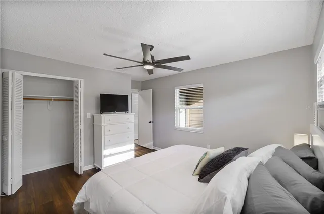 a bedroom with a large bed a flat tv screen and closet
