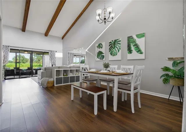 a dining room with wooden floor a chandelier a wooden table and chairs