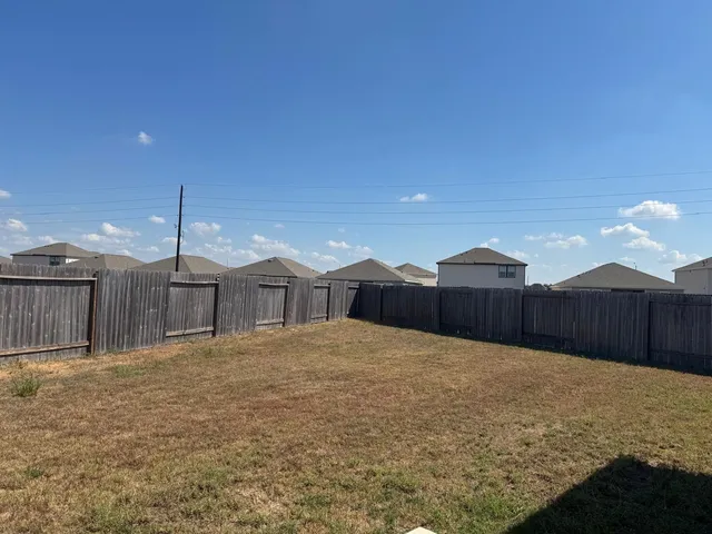 a view of a house with a yard and wooden fence