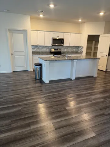 a kitchen with kitchen island granite countertop a stove and a wooden floors