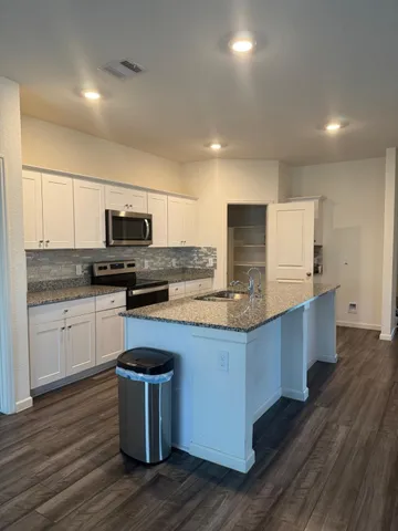 a kitchen with stainless steel appliances white cabinets a sink a stove a microwave and wooden floors