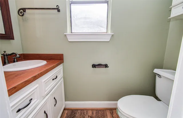 a bathroom with a sink a toilet a window and vanity