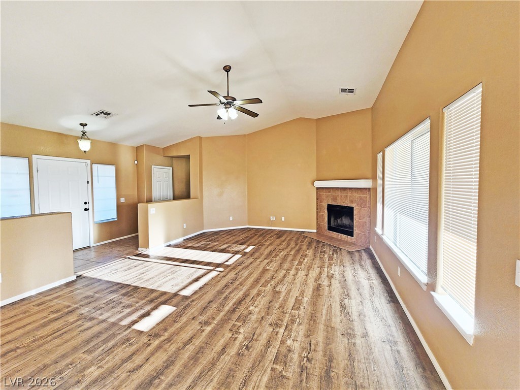 3680 Ravine Avenue Pahrump, NV 89048 - Photo 4 of 28 Unfurnished living room with a tiled fireplace, vaulted ceiling, visible vents, and ceiling fan