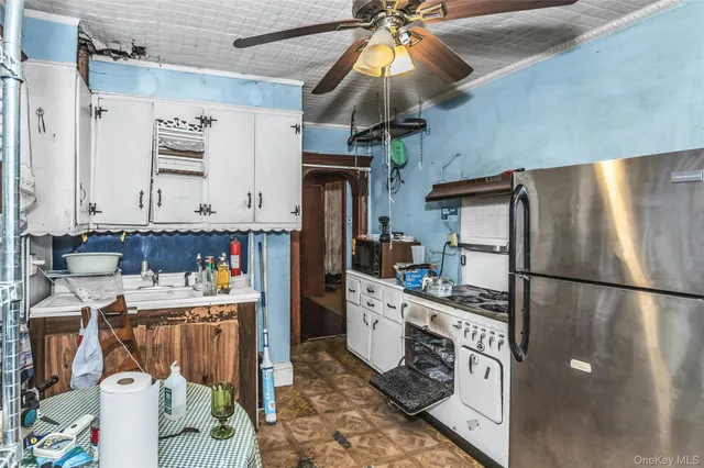 a kitchen with stainless steel appliances a refrigerator a stove a sink and white cabinets