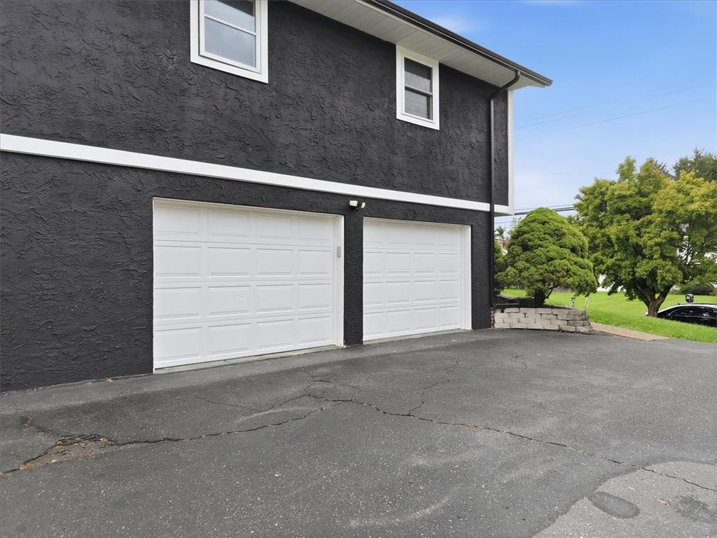 2930 Oakland Road Bethlehem, PA 18017 - Photo 39 of 55 Bold textured stucco walls frame double white garage doors beneath a clear blue sky.