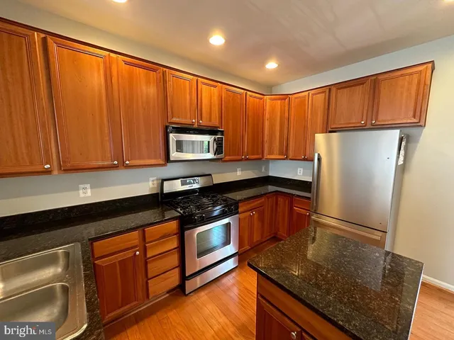 a kitchen with granite countertop wooden cabinets stainless steel appliances a sink and a window