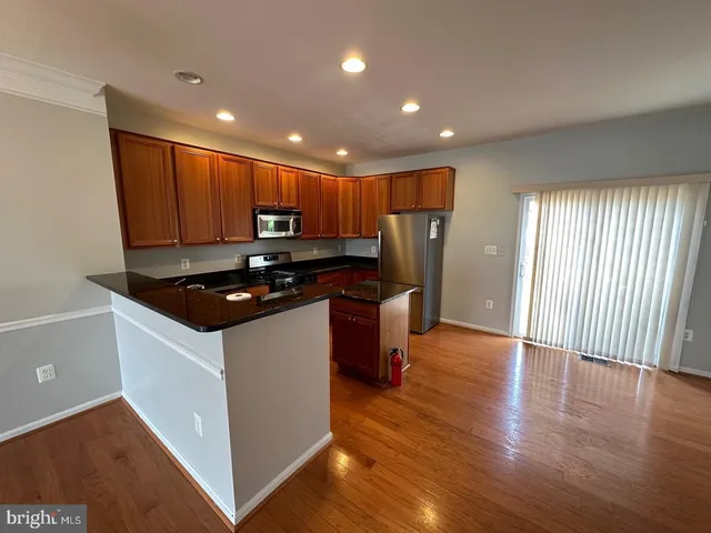 a kitchen with stainless steel appliances granite countertop a refrigerator a sink and wooden floors