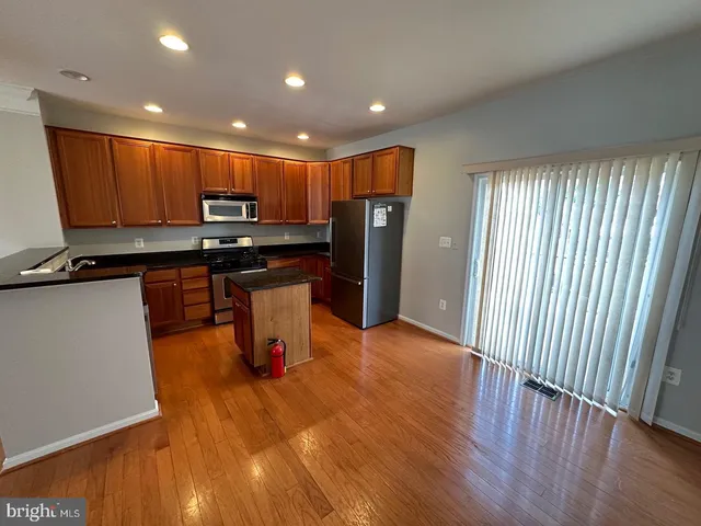 a kitchen with stainless steel appliances wooden floors wooden cabinets and a window