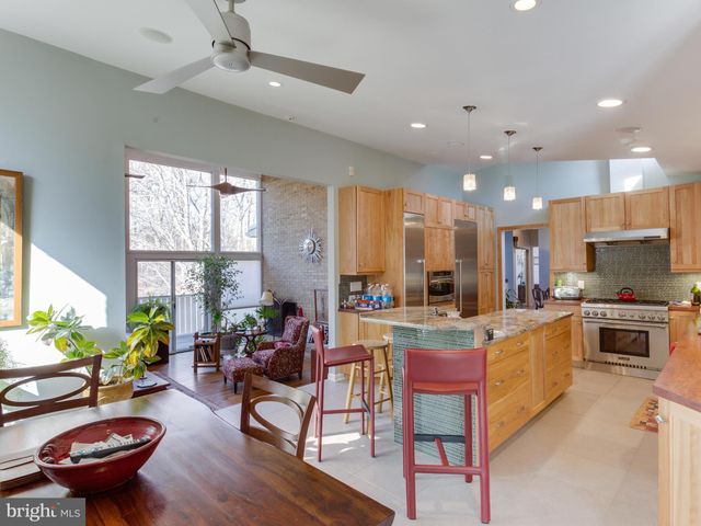 a kitchen with sink a stove and chairs with wooden floor