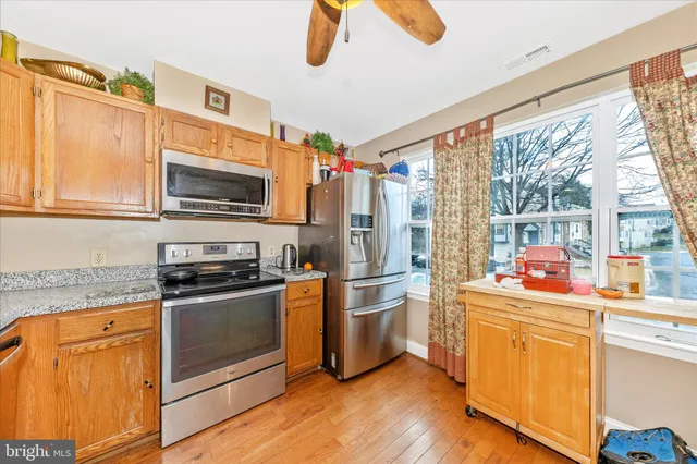 a kitchen with stainless steel appliances granite countertop a refrigerator a stove top oven a sink and dishwasher with wooden floor