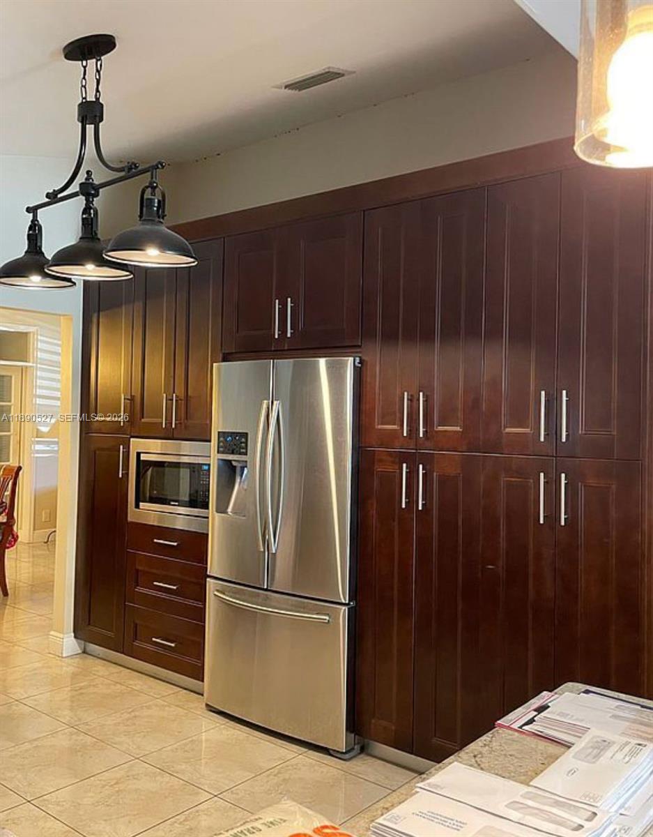 15181 Southwest 156th Terrace Miami, FL 33187 - Photo 11 of 32 a metallic refrigerator freezer sitting in a kitchen