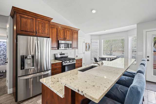 1588 West Rim Rock Drive Stockton, UT 84071 - Photo 12 of 61 Kitchen featuring stainless steel appliances, wood cabinetry, stone countertops, and a bay window
