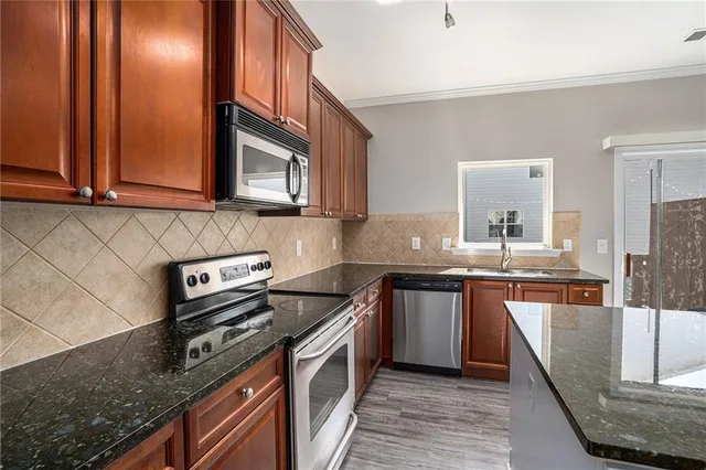 a kitchen with stainless steel appliances granite countertop a stove a sink and a microwave